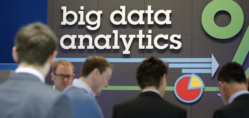 People stand in front of a big data analytics logo at the booth of IBM during preparations for the CeBIT trade fair in Hanover, March 9, 2014.