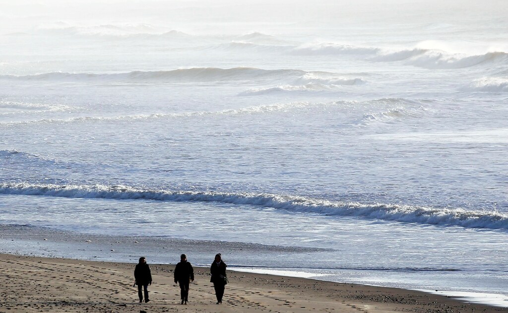 Peoples walk on the beach as waves break along France's Atlantic coastline at sunset in Montalivet-les-bains, France December 19, 2017. REUTERS/Regis Duvignau - RC144450AE30