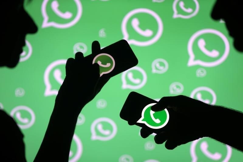 Men pose with smartphones in front of displayed Whatsapp logo in this illustration September 14, 2017. REUTERS/Dado Ruvic - RC1754A449A0