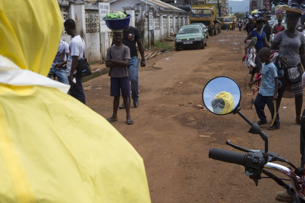 A health worker is reflected in a mirror as he prepares protective equipment near Rokupa Hospital, Freetown October 6, 2014. More than 4,000 people have died of the viral haemorrhagic fever in West Africa, mostly in Liberia, neighbouring Sierra Leone and Guinea. Picture taken October 6, 2014. REUTERS/Christopher Black/WHO/Handout via Reuters (SIERRA LEONE - Tags: DISASTER HEALTH) ATTENTION EDITORS - THIS PICTURE WAS PROVIDED BY A THIRD PARTY. REUTERS IS UNABLE TO INDEPENDENTLY VERIFY THE AUTHENTICITY, CONTENT, LOCATION OR DATE OF THIS IMAGE. FOR EDITORIAL USE ONLY. NOT FOR SALE FOR MARKETING OR ADVERTISING CAMPAIGNS. THIS PICTURE IS DISTRIBUTED EXACTLY AS RECEIVED BY REUTERS, AS A SERVICE TO CLIENTS - RTR4A0NF