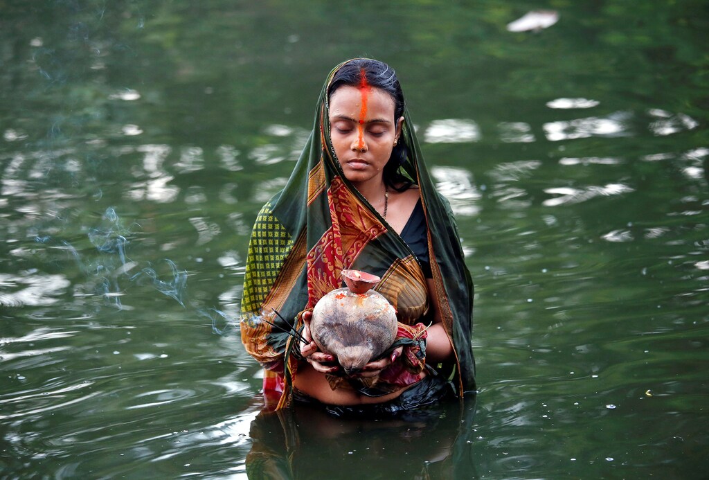 A Hindu devotee holds offerings as she worships the Sun God in the waters of a pond during the religious festival of Chhat Puja in Kolkata, November 7, 2016. REUTERS/Rupak De Chowdhuri TPX IMAGES OF THE DAY - S1AEULKWEGAA