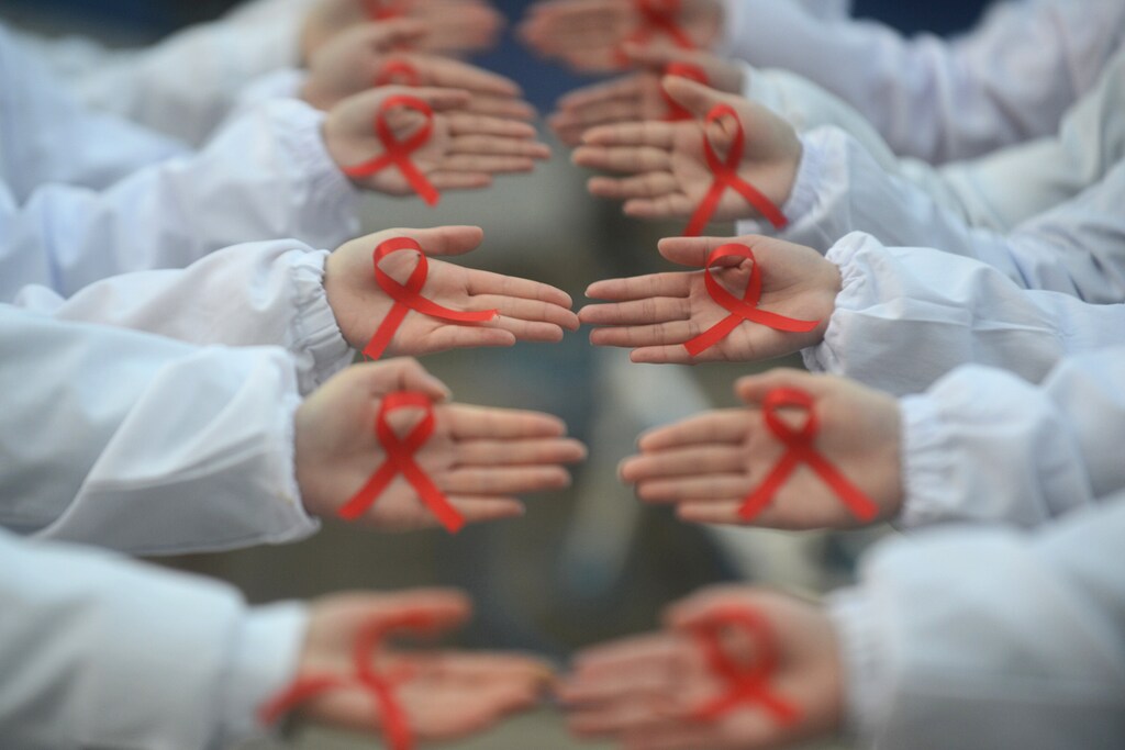 Students hold red ribbons during an event to mark World AIDS Day at a medical college in Yangzhou, Jiangsu province, China November 30, 2017. Picture taken November 30, 2017. REUTERS/Stringer ATTENTION EDITORS - THIS IMAGE WAS PROVIDED BY A THIRD PARTY. CHINA OUT. - RC1385DC1010