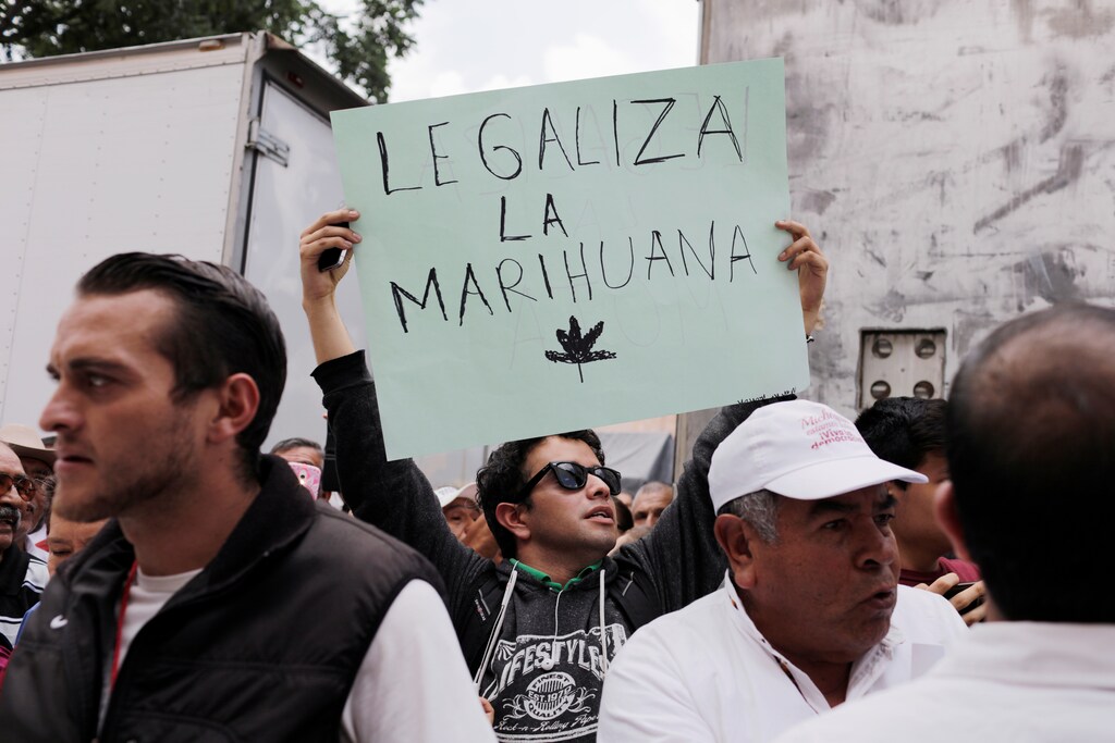 A man holding a sign in a rally by Mexico's President-elect Andres Manuel Lopez Obrador, gestures as part of a tour to thank supporters for his victory in the July 1 election, in Morelia, Mexico, October 6, 2018. The sign reads. "Legalize marijuana". REUTERS/Alan Ortega - RC194DD73B90