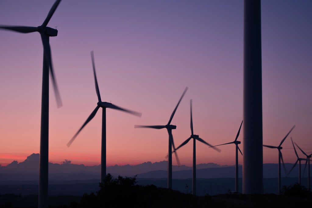 Wind turbines making renewable energy against a pink sky.