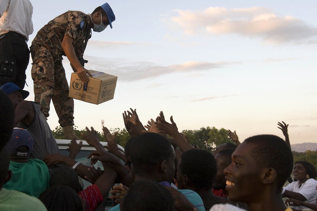 A Jordanian U.N. peacekeeper distributes food to internally displaced Haitians in Port-au-Prince January 18, 2010. U.S. troops protected aid handouts and the United Nations sought extra peacekeepers in earthquake-shattered Haiti on Monday as marauding looters emptied wrecked shops and desperate survivors began to receive medical care and air-dropped food. REUTERS/Logan Abassi/UN Photo/Handout (HAITI - Tags: DISASTER ENVIRONMENT) FOR EDITORIAL USE ONLY. NOT FOR SALE FOR MARKETING OR ADVERTISING CAMPAIGNS - GM1E61J0VBA01