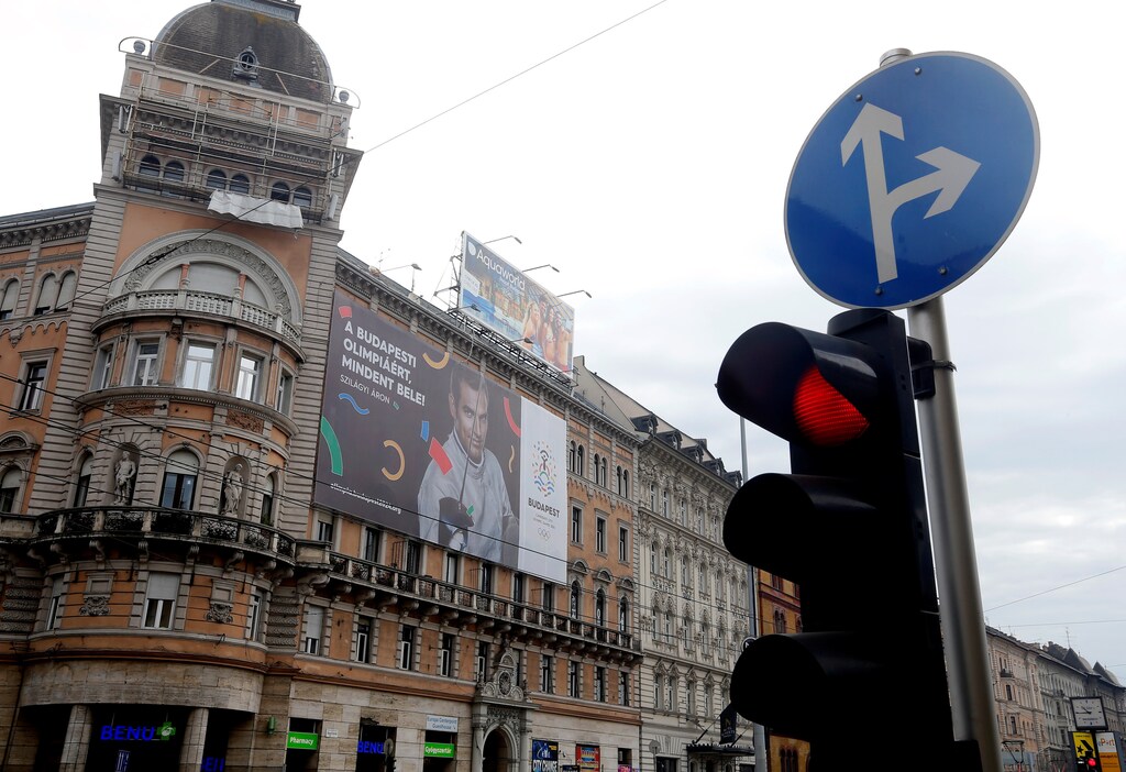 Traffic lights switch to red in front of a Hungarian pro-Olympics billboard with two-times sabre fencing Olympic champion Aron Szilagyi advertising the Games, billboard saying "Give it all for the Budapest Olympics" in central Budapest, Hungary, February 23, 2017. REUTERS/Laszlo Balogh - RTSZYS7