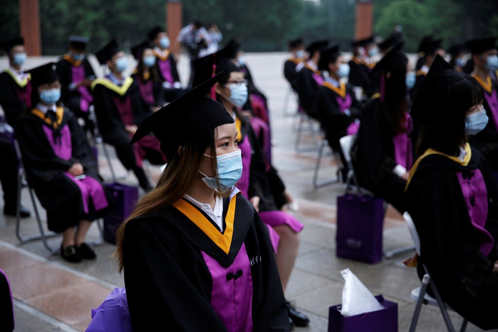 Undergraduate students wearing face masks practice social distancing as they attend a graduation ceremony by watching it live on a screen at Tsinghua University, following the outbreak of the coronavirus disease (COVID-19), in Beijing, China June 23, 2020. REUTERS/Tingshu Wang - RC2SEH9AOTUB