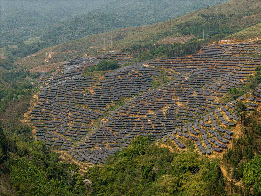 Solar panels with a backdrop of rolling green landscape in China, Yunnan, Kunming, Wuhua District.