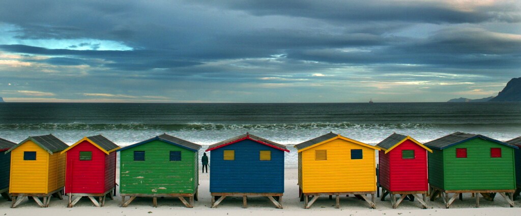 A lone stroller stares out to sea beyond a row of beach huts as a cold frontsets in over Muizenberg in Cape Town, August 12, 2003. NO RIGHTS CLEARANCES OR PERMISSIONS ARE REQUIRED FOR THIS IMAGEREUTERS/Mike Hutchings 2004 CALENDAR PP03100133MH/SN - RP4DRIFSICAC