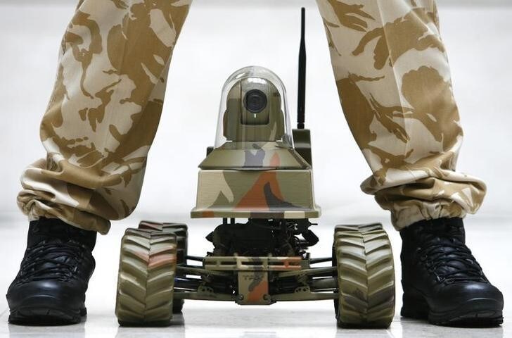 A Royal Marine poses for photographers with the Unmanned Vehicle Robot, Testudo, at the launch of the Defence Technology Plan in London February 26, 2009. The media were invited to the launch of the Defence Technology Plan. This is the first time the Ministry of Defence has publicly revealed its research needs. REUTERS/Luke MacGregor (BRITAIN)