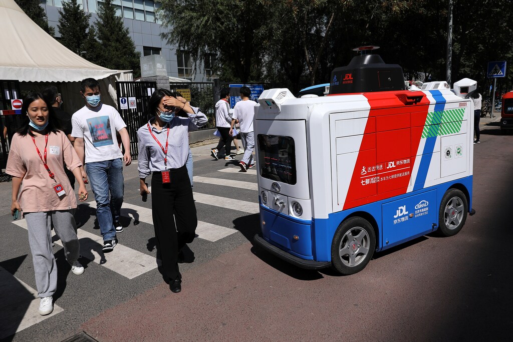 People walk past an autonomous delivery vehicle by JD Logistics, the delivery arm of JD.com, in Beijing, China.