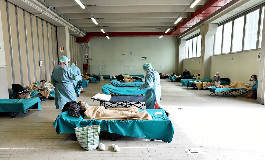 Medical personnel wearing protective face masks help patients inside the Spedali Civili hospital in Brescia, Italy March 13, 2020