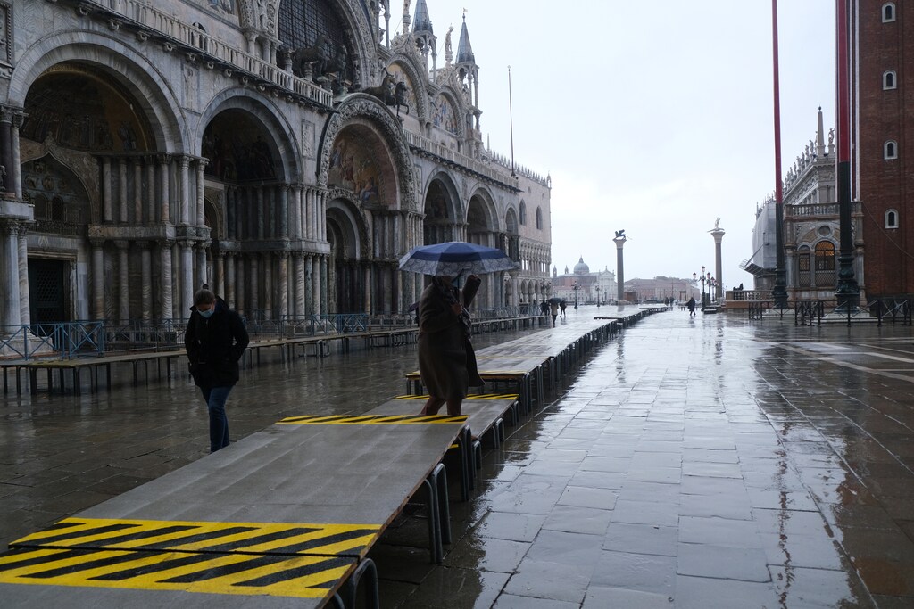 People walk in St. Mark's Square during high tide on makeshift catwalks as the flood barriers known as Mose are raised for the second time, successfully protecting the lagoon city from flooding, in Venice.