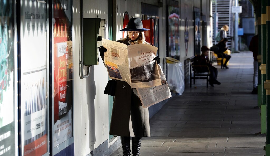 A woman reads a newspaper whilst waiting for a tube train on an autumn morning in London, Britain, October 30, 2017.