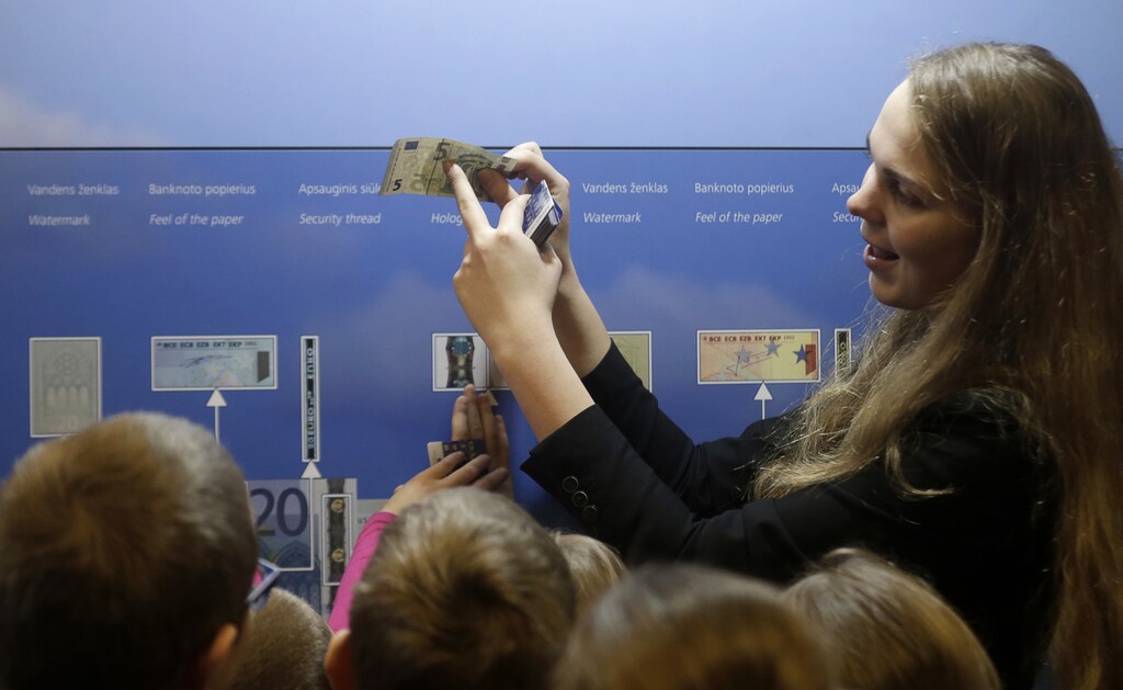 A guide shows the security features of euro banknotes to students in Vilnius December 17, 2014. Tensions with Moscow have simmered ever since Lithuania became the first republic to declare independence from the Soviet Union in 1990, although only 6 percent of the population are Russian speakers, far fewer than in its Baltic neighbours. On Jan. 1, it will be the last of the Baltic states to join the currency bloc, hoping like Estonia and Latvia for more investment and lower borrowing costs to spur one of Europe?s poorest but fastest-growing economies. All three have felt the blowback from East-West tension over Russia's encroachment into Ukraine this year in the form of Russian sanctions and military grandstanding on their borders. Picture taken December 17, 2014. REUTERS/Ints Kalnins (LITHUANIA - Tags: POLITICS BUSINESS) - RTR4ITLX