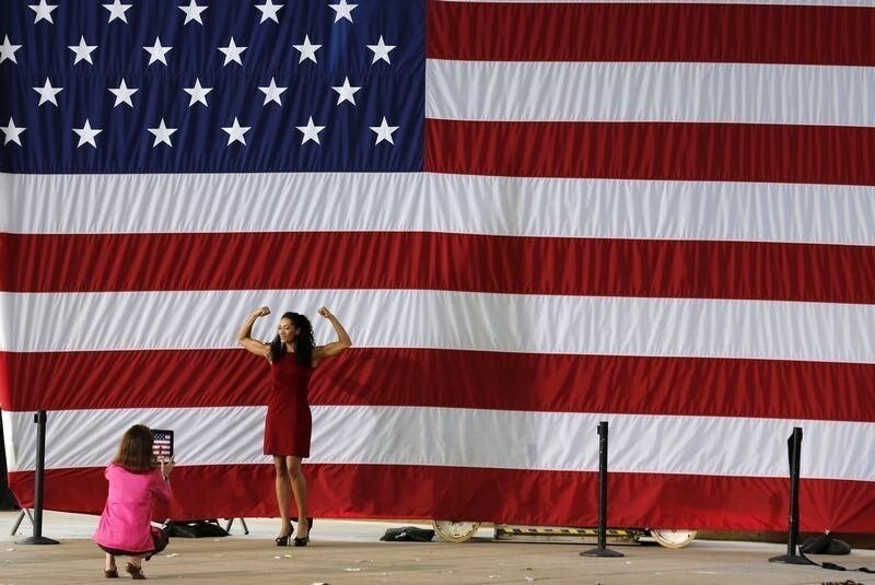 Monica Cabbler poses for a friend with a camera in front of the American flag after U.S. President Barack Obama speaks at a campaign event at the Charlottesville nTelos Wireless Pavillion in Virginia, August 29, 2012. REUTERS/Larry Downing (UNITED STATES - Tags: POLITICS ELECTIONS) FOR BEST QUALITY IMAGE: ALSO SEE GF2E8BD1E3501. - RTR378WS
