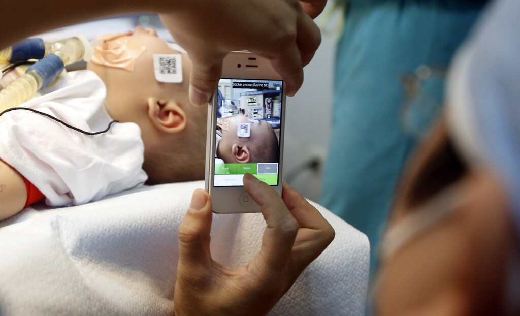 A doctor uses a smartphone to take a photo of a child with facial deformity before surgery at the Vietnam Cuba hospital in Hanoi November 18, 2014. As many as 300 multinational medical volunteers from Operational Smile, a worldwide children's charity, will provide free cleft surgery to over 1,000 children from November 17 to November 25, according to its press release. The charity will also commemorate its 25th anniversary mission to Vietnam in November at six sites simultaneously in Hanoi, Ho Chi Minh City, Hue, Da Nang, Nha Trang and Bac Lieu, it said in a statement. REUTERS/Kham (VIETNAM - Tags: HEALTH SOCIETY) - GM1EABI1JZ101