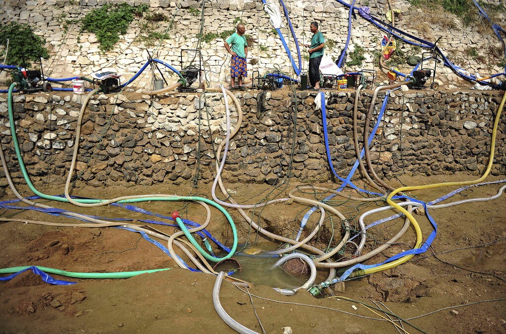 Villagers use pumps to get water from a partially dried-up pond as drought hits Penglai, Shandong province, China, July 8, 2015. Severe drought hit part of Shandong province in eastern China due to lack of substantial rainfalls since this spring, local media reported. REUTERS/China Daily