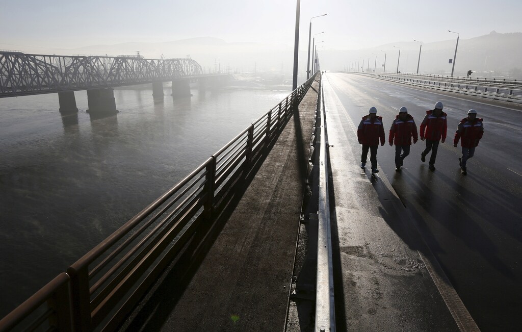 Engineers walk along a new highway bridge before an opening ceremony, with the Yenisei River and a bridge of the Trans-Siberian Railway seen nearby, in the Siberian city of Krasnoyarsk, Russia, October 29, 2015. The construction of the 1273,35-metre-long highway bridge, connecting the M-53 "Baikal" and M54 "Yenisei" federal highways, began in October 2011 and cost about 12 billion Russian roubles, according to local media. The Yenisei divides Siberia between Western and Eastern (back) parts while the bridge serves as a link between them. REUTERS/Ilya Naymushin - RTX1TSFR