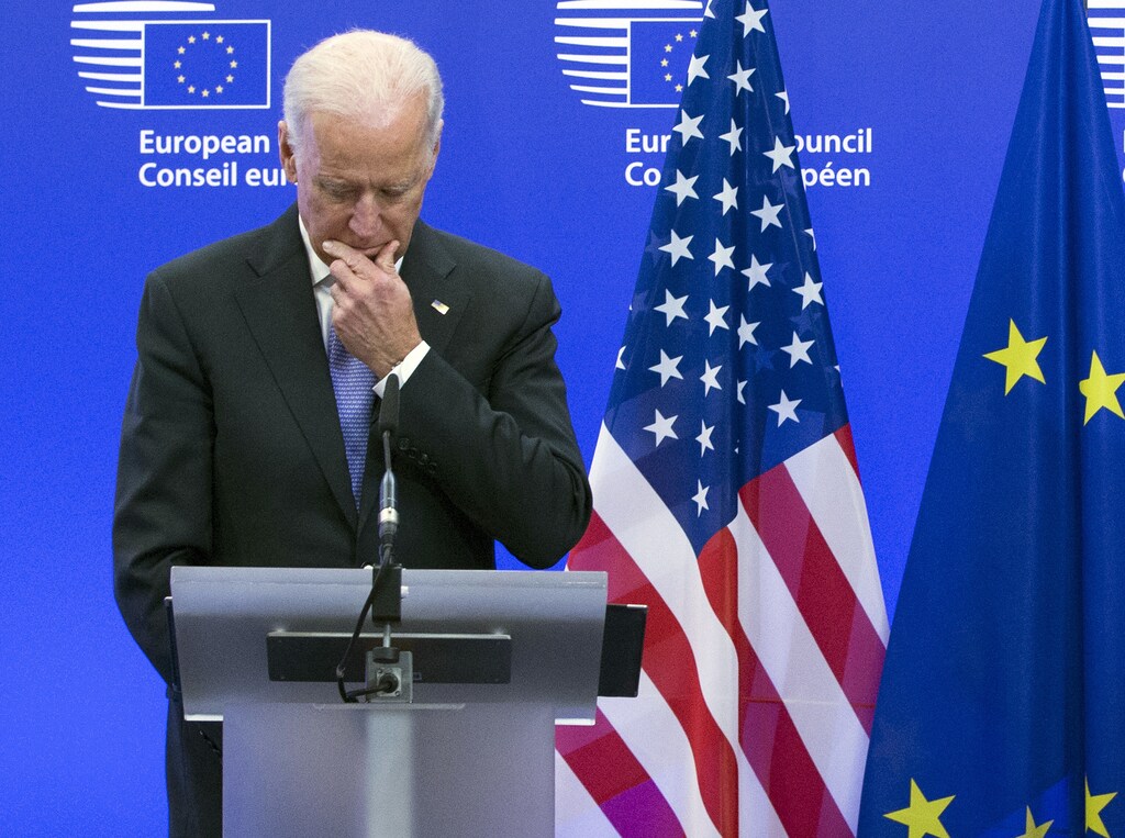 US president Joe Biden stands in front of the US and EU flag