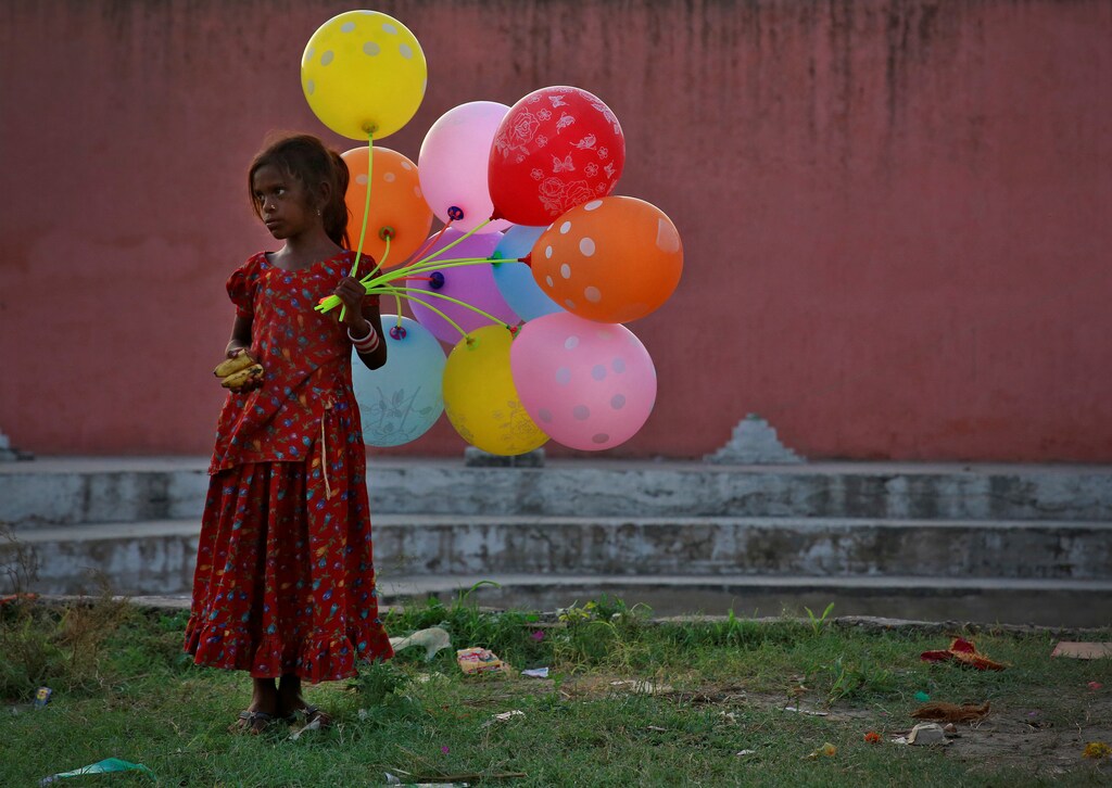 A young girl sells balloons by the Yamuna River as devotees carrying idols of the Hindu god Ganesh, the deity of prosperity, immerse the idol on the last day of the ten-day-long Ganesh Chaturthi festival in Delhi, India, September 15, 2016. REUTERS/Cathal McNaughton TPX IMAGES OF THE DAY - RTSNWSK