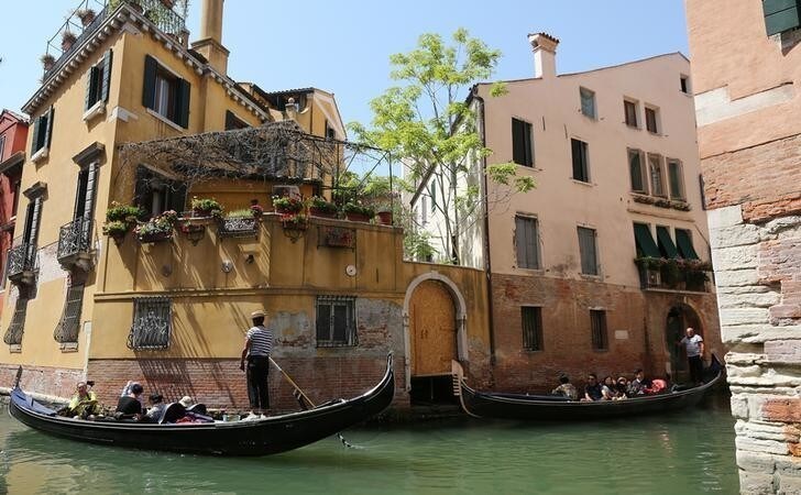 Gondoliers row as tourists enjoy a ride along a canal near St. Mark's Square in Venice, Italy, August 3, 2017. REUTERS/Stefano Rellandini