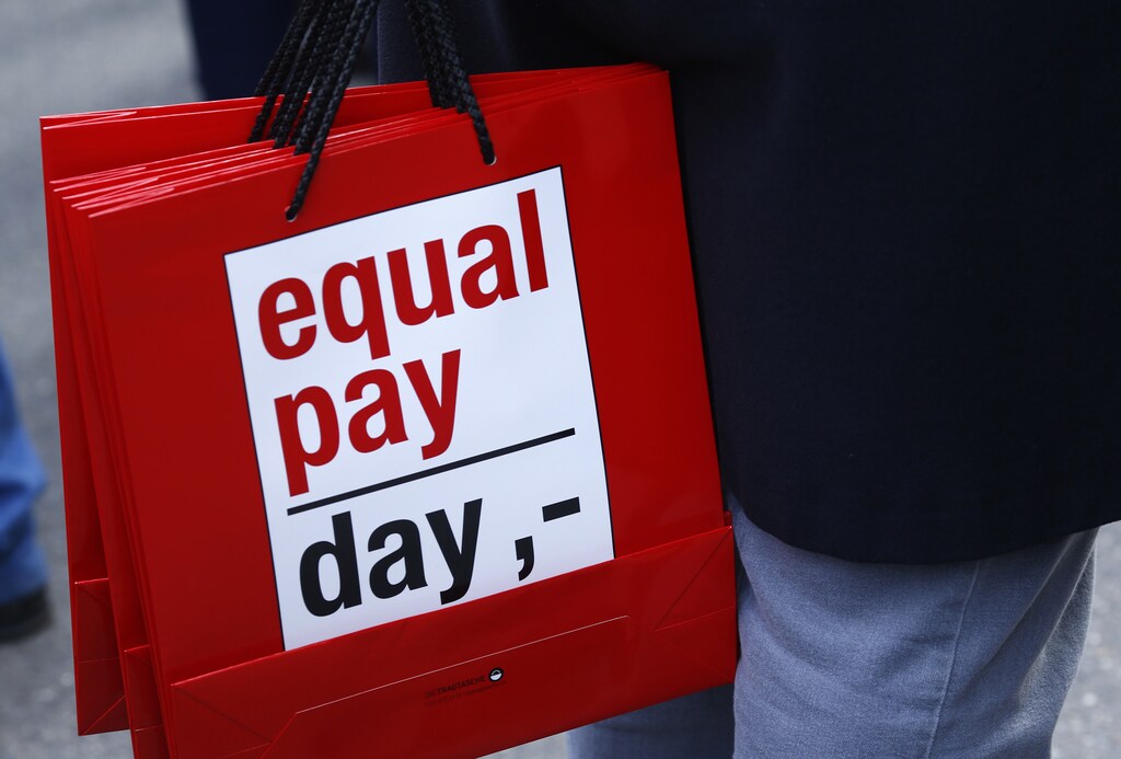 People carry bags reading 'equal pay day' during a protest a day before International Women's Day