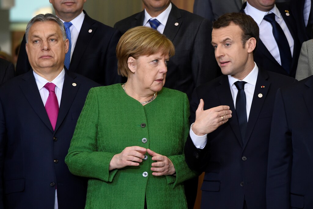 France's president Emmanuel Macron speaks with German chancellor Angela Merkel next to Hungary's prime minister Viktor Orban.