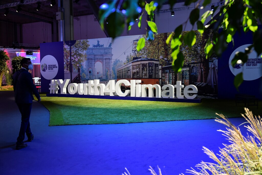 A man walks next to a sign of the Youth4Climate conference in Milan, Italy, September 28, 2021. REUTERS/Flavio Lo Scalzo - RC2WYP94UQQC