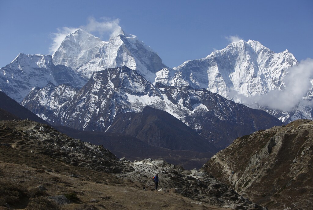 A trekker walks in front of Mount Thamserku while on his way back from Everest base camp near Pheriche in Solukhumbu District May 3, 2014. More than 4,000 climbers have reached the summit of Everest, the world's highest peak, since it was first scaled by Sir Edmund Hillary and Tenzing Norgay Sherpa in 1953. In April, an avalanche killed 16 Nepali Sherpa guides who were fixing ropes and ferrying supplies for their foreign clients to climb the 8,850-metre (29,035-foot) peak. The accident - the deadliest in the history of Mount Everest - triggered a dispute between sherpa guides who wanted a climbing ban in honour of their colleagues and the Nepali government that refused to close the mountain. The sherpas staged a boycott, forcing hundreds of foreign climbers to call off their bids to climb Everest. Picture taken May 3, 2014. REUTERS/Navesh Chitrakar (NEPAL - Tags: ENVIRONMENT SOCIETY BUSINESS EMPLOYMENT TRAVEL)ATTENTION EDITORS: PICTURE 35 OF 45 FOR PACKAGE 'AFTER THE AVALANCHE - ASCENT TO EVEREST'TO FIND ALL IMAGES SEARCH 'CHITRAKAR EVEREST' - RTR3SBI8