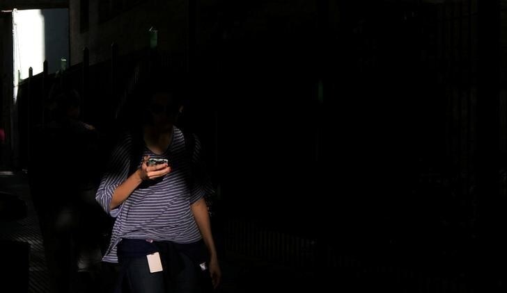 A woman uses her mobile phone as she walks on a street in Buenos Aires, Argentina, March 15, 2018. Picture taken March 15, 2018. REUTERS/Marcos Brindicci