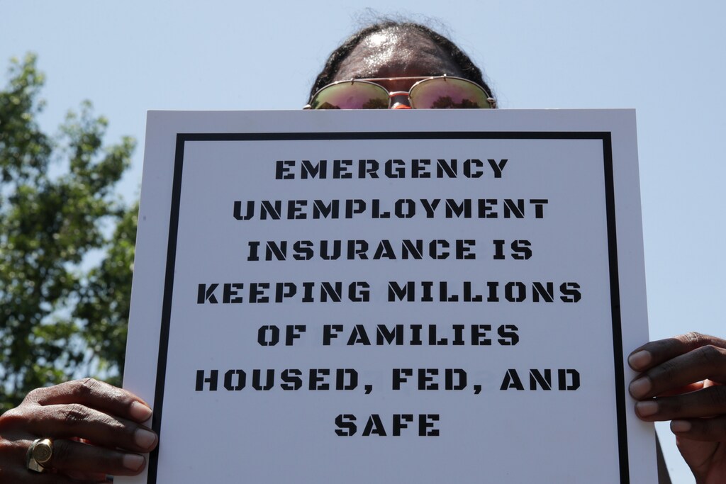 A person holds a placard as protesters temporarily block the street to U.S. Senate Majority Leader Mitch McConnell's (R-KY) house with a live band on a flatbed truck, demanding the extension of coronavirus disease (COVID-19)-related unemployment aid, on Capitol Hill in Washington, U.S. July 22, 2020. REUTERS/Jonathan Ernst - RC2JYH9ELMKL