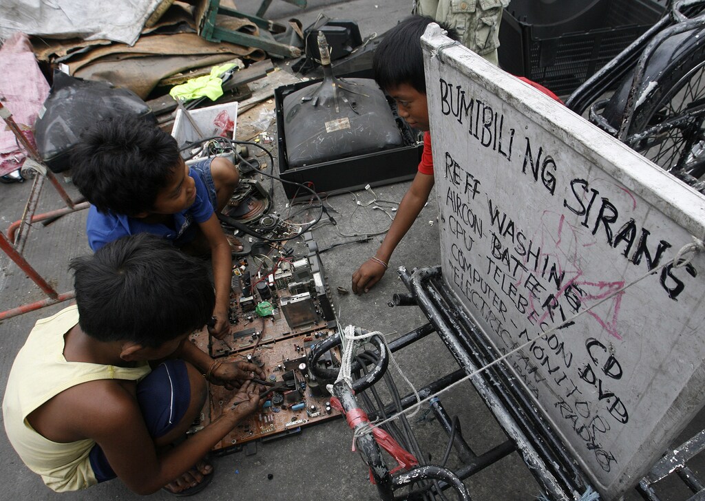 Children recover copper and other metals from discarded televisions and other electronic waste, which they exchange for money from nearby junkshops, along a road in Manila April 7, 2011. An e-waste recycling and reclamation company salvages gold and other precious metals like silver, copper and palladium from microprocessors of discarded electronic products like desktop computers, laptops, mobile phones and copying machines. About 4000 integrated circuits from discarded mobile phones can produce about 100 grams of gold. REUTERS/Cheryl Ravelo (PHILIPPINES - Tags: SOCIETY EMPLOYMENT BUSINESS ENVIRONMENT) - GM1E7480PWO01