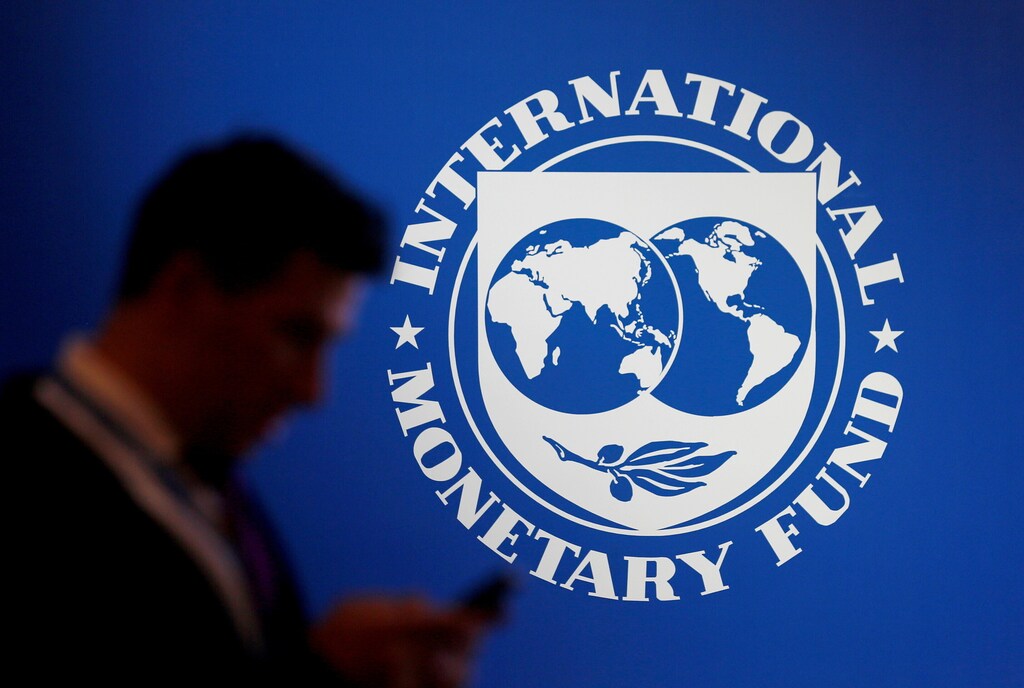 Un hombre camina delante de un logotipo del FMI.