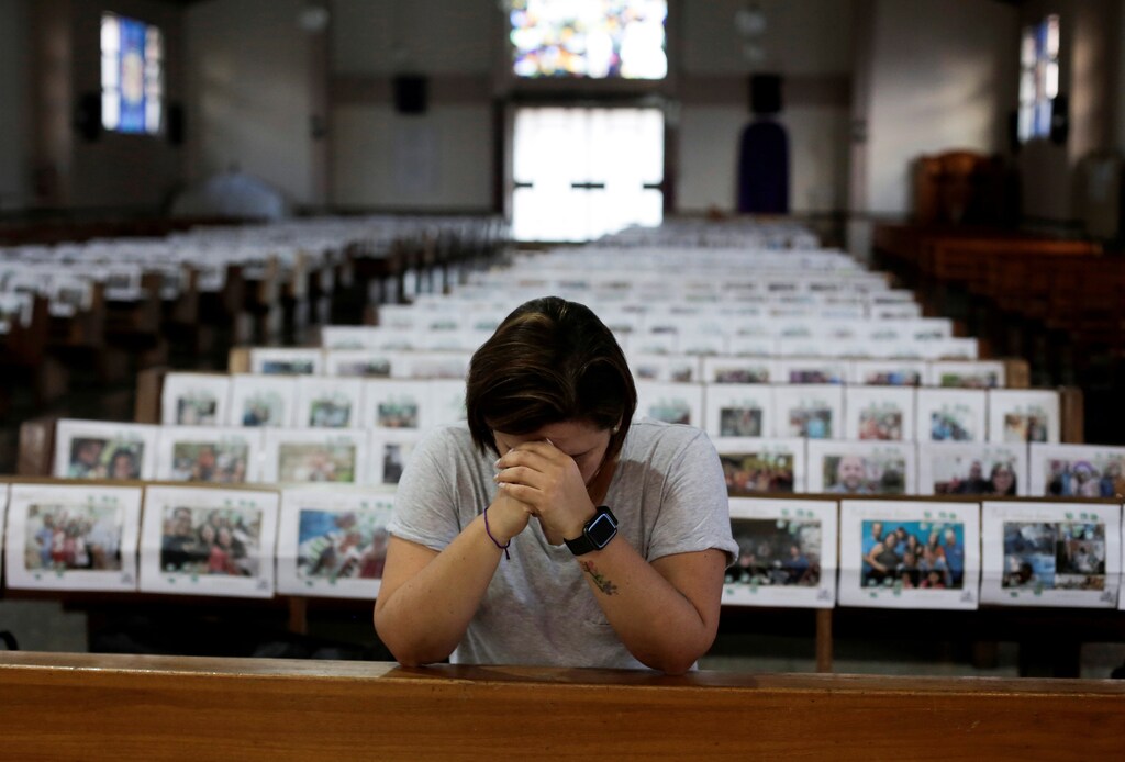 Adriana Brenes reza durante una misa transmitida en vivo mientras se exhiben fotos de los fieles sobre los bancos de la iglesia de Nuestra Señora de Fátima, mientras continúa la propagación de la enfermedad coronavirus (COVID-19), en San José, Costa Rica, el 8 de abril de 2020.