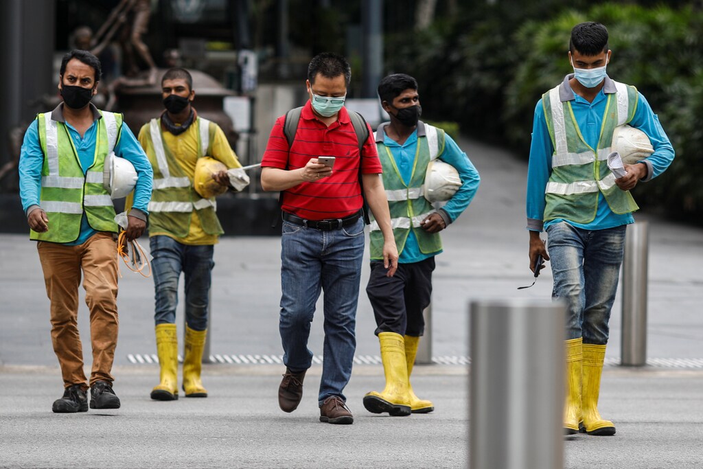 Migrant workers in essential services wearing safety vests cross a street at Orchard Road, amid the coronavirus disease (COVID-19) outbreak in Singapore, May 27, 2020. REUTERS/Edgar Su - RC2TWG9L17PT