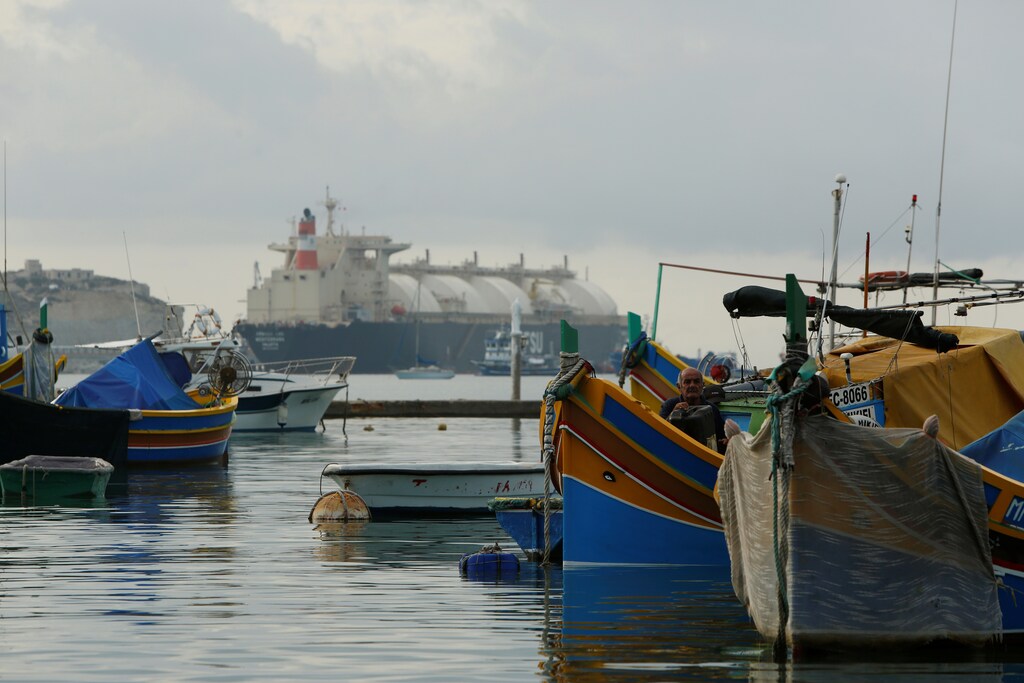 A fisherman sits in his 'luzzu' fishing boat after the LNG tanker MV Armada Mediterrana (rear) arrived in Marsaxlokk Bay outside one of Malta's prime tourist spots, the traditional fishing village of Marsaxlokk in the south of Malta, October 10, 2016. Mired in political controversy because of safety concerns, the tanker will be permanently moored at Marsaxlokk Bay, where it will serve as a floating storage unit for a new gas-fired power station, according to local media.REUTERS/Darrin Zammit Lupi MALTA OUT. NO COMMERCIAL OR EDITORIAL SALES IN MALTA - RTSRMEW