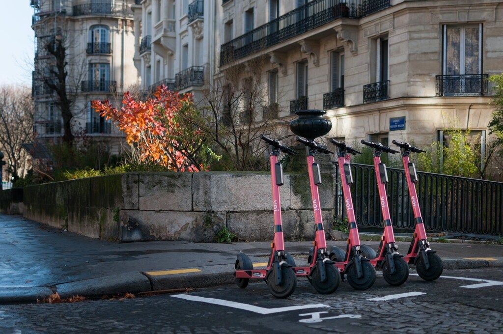 5 e-scooters parked by the side of a road.