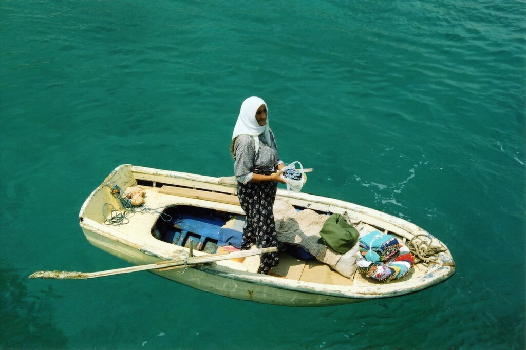 a woman fishes from a rowing boat in Turkey