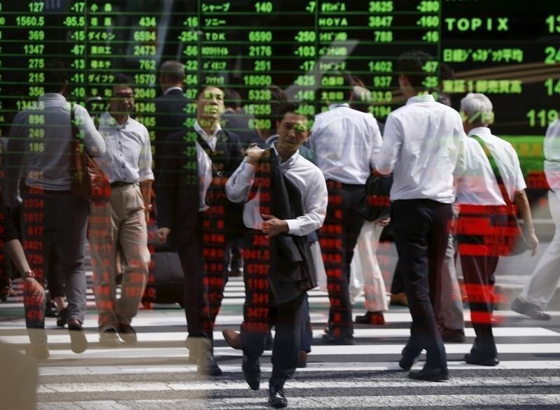 Passersby are reflected on a stock quotation board at a brokerage in Tokyo, Japan, September 29, 2015. Asian shares skidded to 3-1/2-year lows and the dollar sagged on Tuesday, pulled down by a sharp losses on Wall Street after weak Chinese data rekindled worries about its fragile economy. REUTERS/Issei Kato TPX IMAGES OF THE DAY - GF10000225939