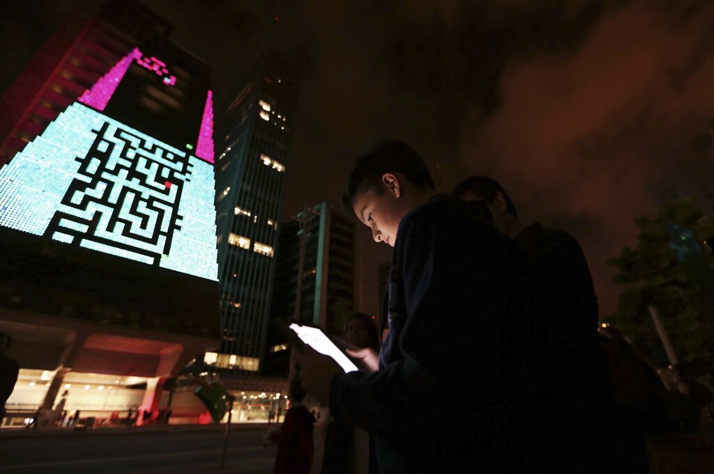 A boy uses an iPad to play a video game, which is projected onto the surface of the Fiesp building, headquarters of the Industry Federation of Sao Paulo, during the "Play!" exhibition in the financial center of Sao Paulo's Avenida Paulista March 27, 2013. The exhibition aims to explore the possibilities of integrating digital art in public space through new communication tools, according to the curator of the event. The games presented in the exhibition are from the 1970s and 80s. REUTERS/Nacho Doce (BRAZIL - Tags: SCIENCE TECHNOLOGY SOCIETY TPX IMAGES OF THE DAY) - GM1E93S0YJJ01
