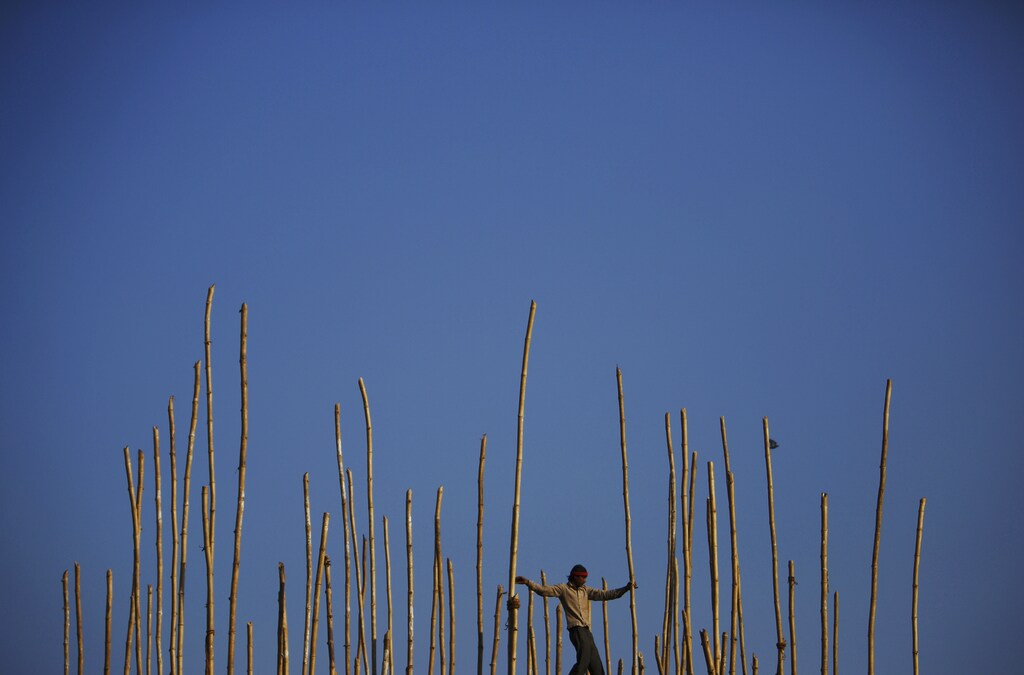 A migrant labourer from India balances himself as he walks on bamboo scaffolding while constructing the Vaishno Devi Temple, measuring 24 metres (79 feet) in height, at the premises of Pashupatinath Temple in Kathmandu January 20, 2014. REUTERS/Navesh Chitrakar (NEPAL - Tags: RELIGION SOCIETY IMMIGRATION BUSINESS EMPLOYMENT CONSTRUCTION TPX IMAGES OF THE DAY) - GM1EA1K1J0C01