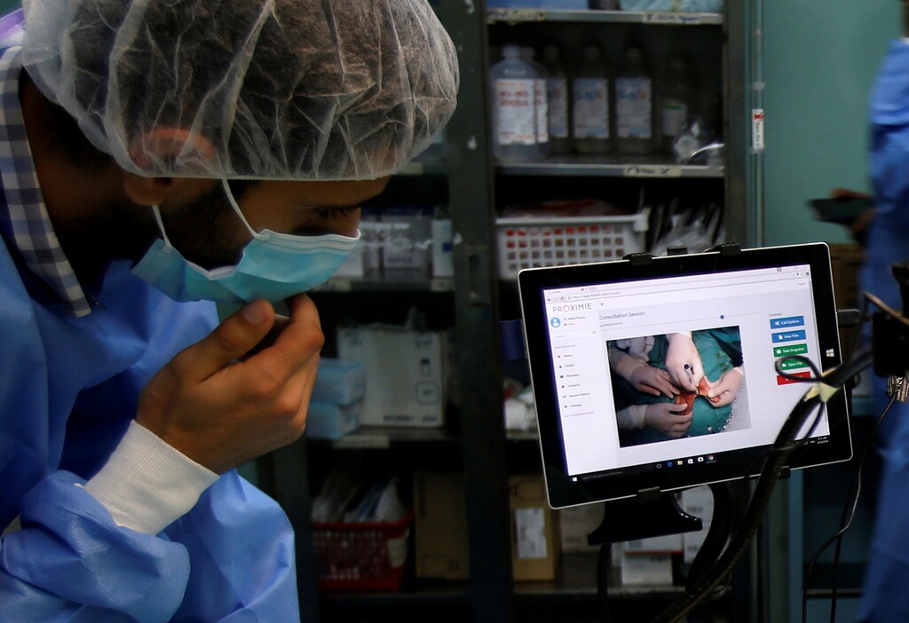 A technician looks at a screen during a Proximie surgery, with doctor Ghassan Abu Sitta in Beirut guiding Palestinian surgeon Hafez Abu Khousa, in the operating room at Al Awda Hospital in the northern Gaza Strip April 30, 2016. REUTERS/Suhaib Salem - RTX2CTVT