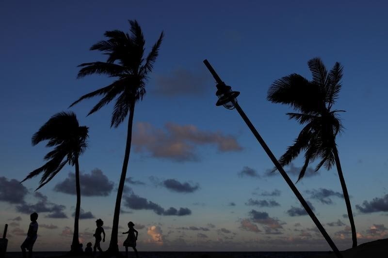 People are seen in silhouette walking on a beach affected by Hurricane Maria in San Juan, Puerto Rico, October 13, 2017. REUTERS/Shannon Stapleton - RC1AB7C48290