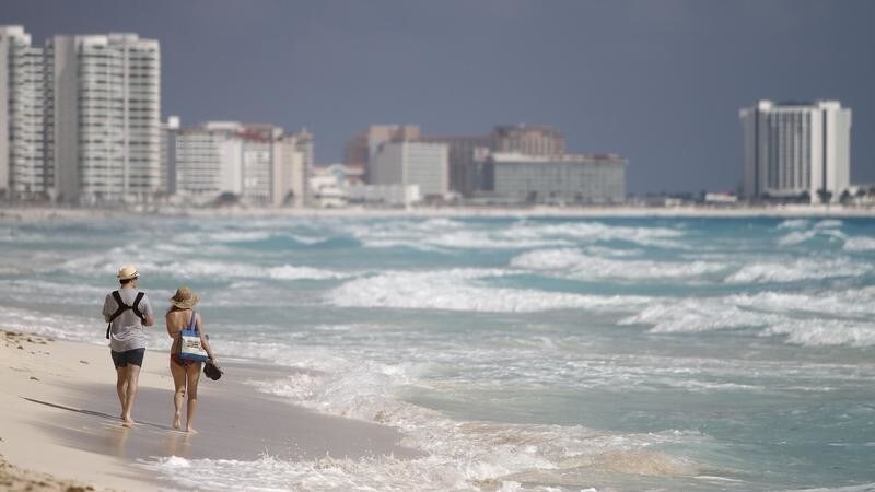 A couple walks along Marlin beach in Cancun February 1, 2011. Mexico is seeking to overhaul its image abroad after a raft of bad publicity over drug related violence, beheadings and shootings has taken its toll on the holiday industry. Foreign tourism is a key source of income in Mexico and the country wants to reclaim its share of the market by reminding potential visitors about its wonderful beaches and archaeological sites. REUTERS/Gerardo Garcia (MEXICO - Tags: POLITICS TRAVEL CRIME LAW BUSINESS) - GM1E72208UY01