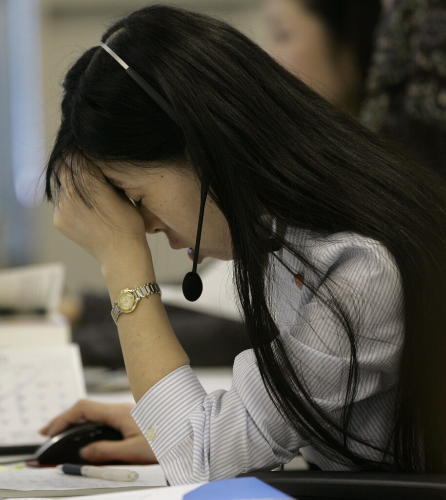 A call center personnel presses her hand to her forehead at an online brokerage company in Tokyo October 23, 2008. The Nikkei average fell 5.5 percent on Thursday and hit its lowest point in more than five years, with exporters such as Canon battered by a firmer yen and fears over the health of the global economy. REUTERS/Yuriko Nakao(JAPAN) - GM1E4AN0TZN01