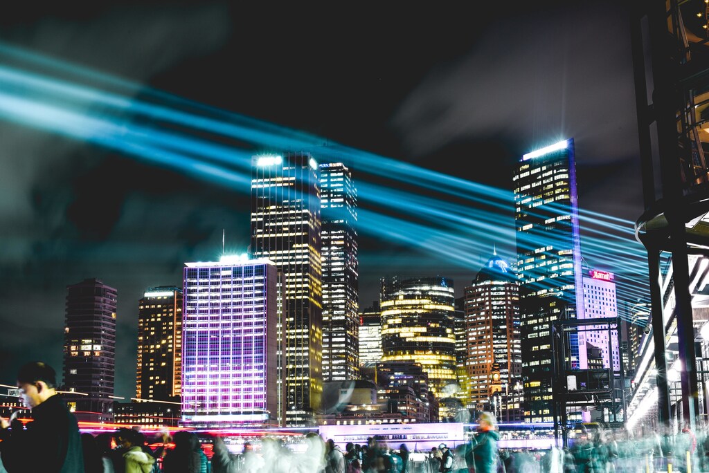 Image shows a cityscape at light with beams of what could illustrate smart technology strobing across smart cities.