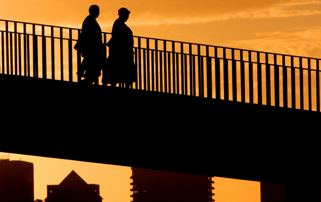 Two domestic workers cross a bridge against the Cape Town city skyline asthey return home at the days end in this July 2002 file picture. Almost nineyears after the end of white rule, huge income disparities still persist inNelson Mandela's "Rainbow Nation". Disturbingly, recent research byStatistics South Africa suggests that income inequalities, which still runlargely but not exclusively along racial lines, may actually be growing.NO RIGHTS CLEARANCES OR PERMISSIONS ARE REQUIRED FOR THIS IMAGE REUTERS/Mike HutchingsMH/WS - RP3DRILNFZAA