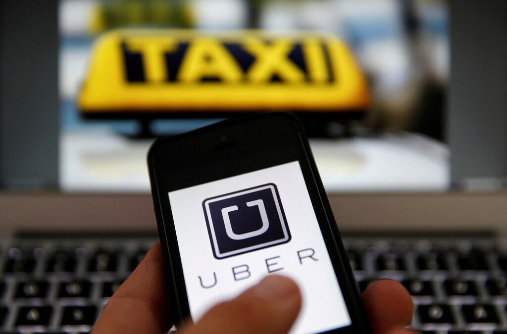 An illustration picture shows the logo of car-sharing service app Uber on a smartphone next to the picture of an official German taxi sign September 15, 2014. REUTERS/Kai Pfaffenbach/Illustration/File Photo - RTX2LQQH