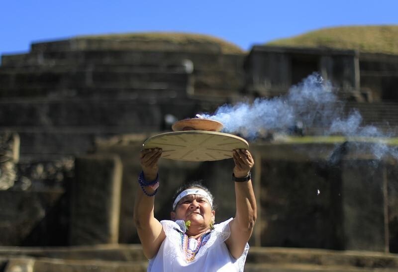 Mayte Dominuez, shaman of the town of Cuisnahuat, holds up the sacred fire during a ceremony at the Maya archeological site of Tazumal in Santa Ana, about 75 km (47 miles) away from San Salvador December 21, 2012. Mystics, hippies and tourists descended on the ruins of Maya cities to mark the close of the 13th bak'tun - a period of around 400 years - and many hoped it would lead to a better era for humanity. This week, at sunrise on Friday, December 21, an era closes in the Maya Long Count calendar, an event that has been likened by different groups to the end of days, the start of a new, more spiritual age or a good reason to hang out at old Maya temples across Mexico and Central America. REUTERS/Ulises Rodriguez (EL SALVADOR - Tags: SOCIETY) - GM1E8CM0E4I01